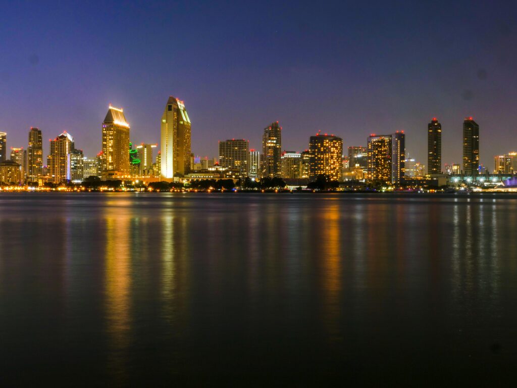Captivating view of San Diego skyline reflecting on the water at night with city lights.